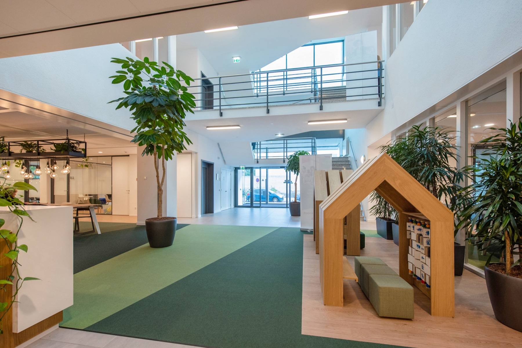 De open begane grond van het atrium, met beplanting en een houten speelhuis voor de bezoekers van de huurder.