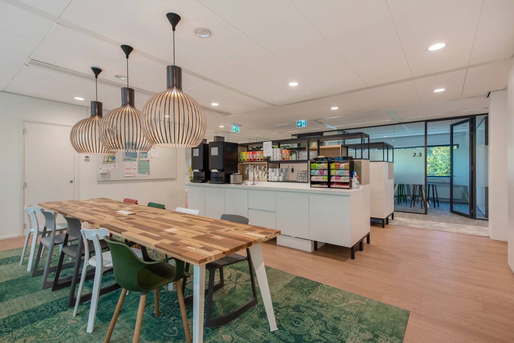 Het cafégedeelte van het gebouw, met een lange houten tafel en een koffiebar.